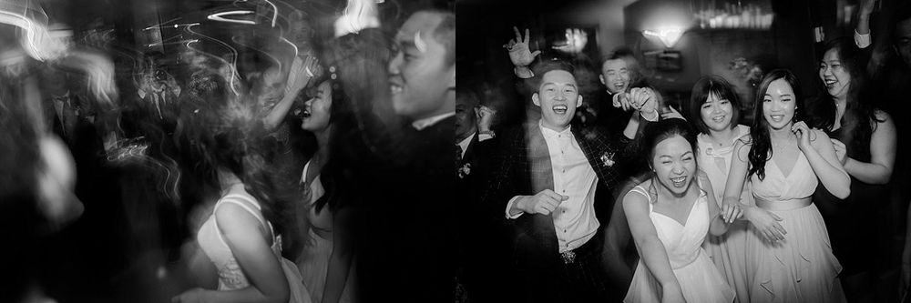 Black and white photo of guests dancing at a lively wedding reception.