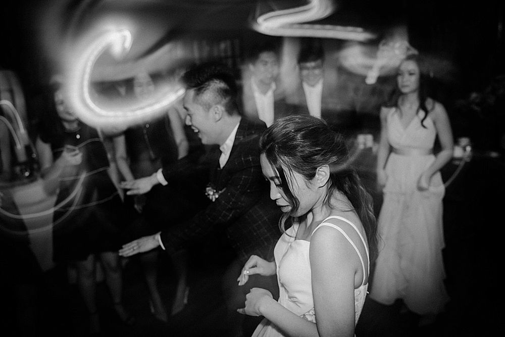 Dark reception hall filled with party guests dancing under ambient lighting.