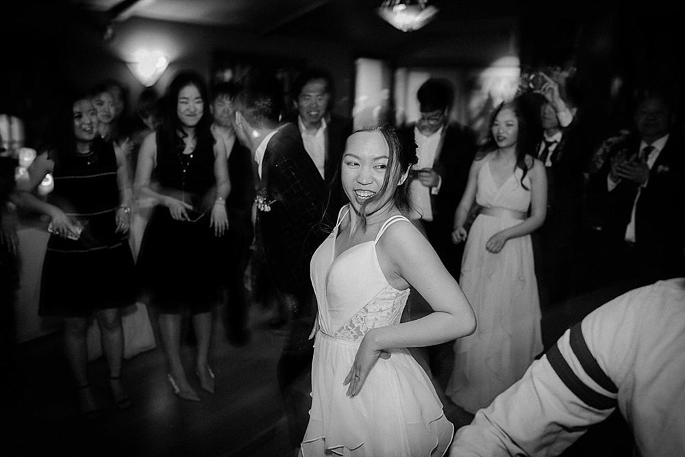 Wedding guests moving energetically on a dimly lit dance floor during reception celebrations.