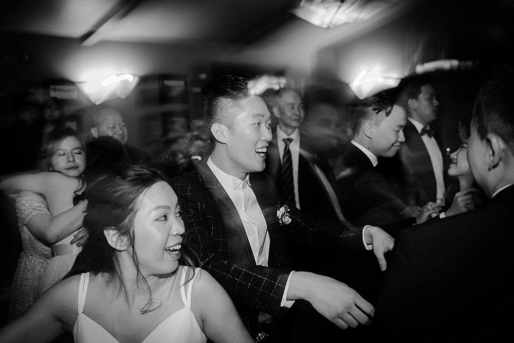 Black and white photograph showing silhouettes of people dancing at an evening event.