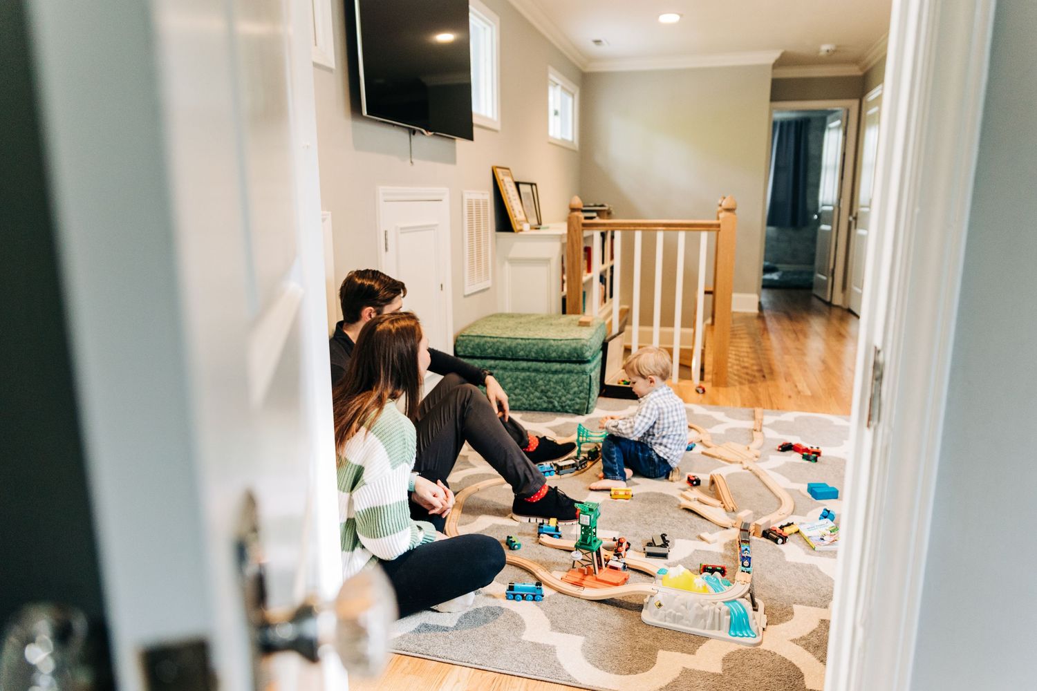 Parents watching their son play with toy trains in their Charlotte home