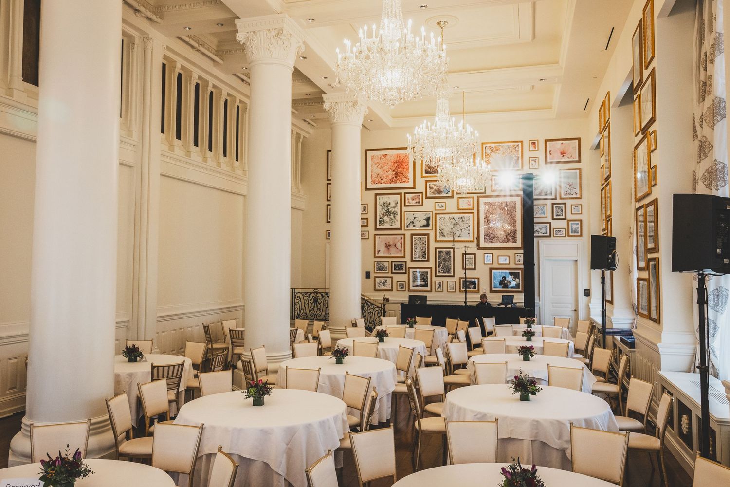 Elegant dining room with white tablecloths, crystal chandelier and art-covered walls.