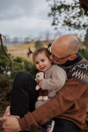 A sweet moment between parent and child wearing matching knit sweaters outdoors.
