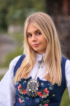 A detailed view of a traditional Norwegian bunad dress with ornate silver brooch and floral embroidery.