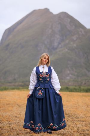 Traditional Nordic folk costume photographed against a dramatic mountain landscape.