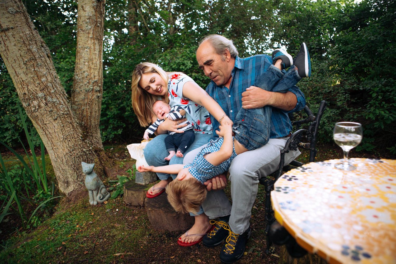 A casual outdoor family gathering with laughter around a garden table at dusk.