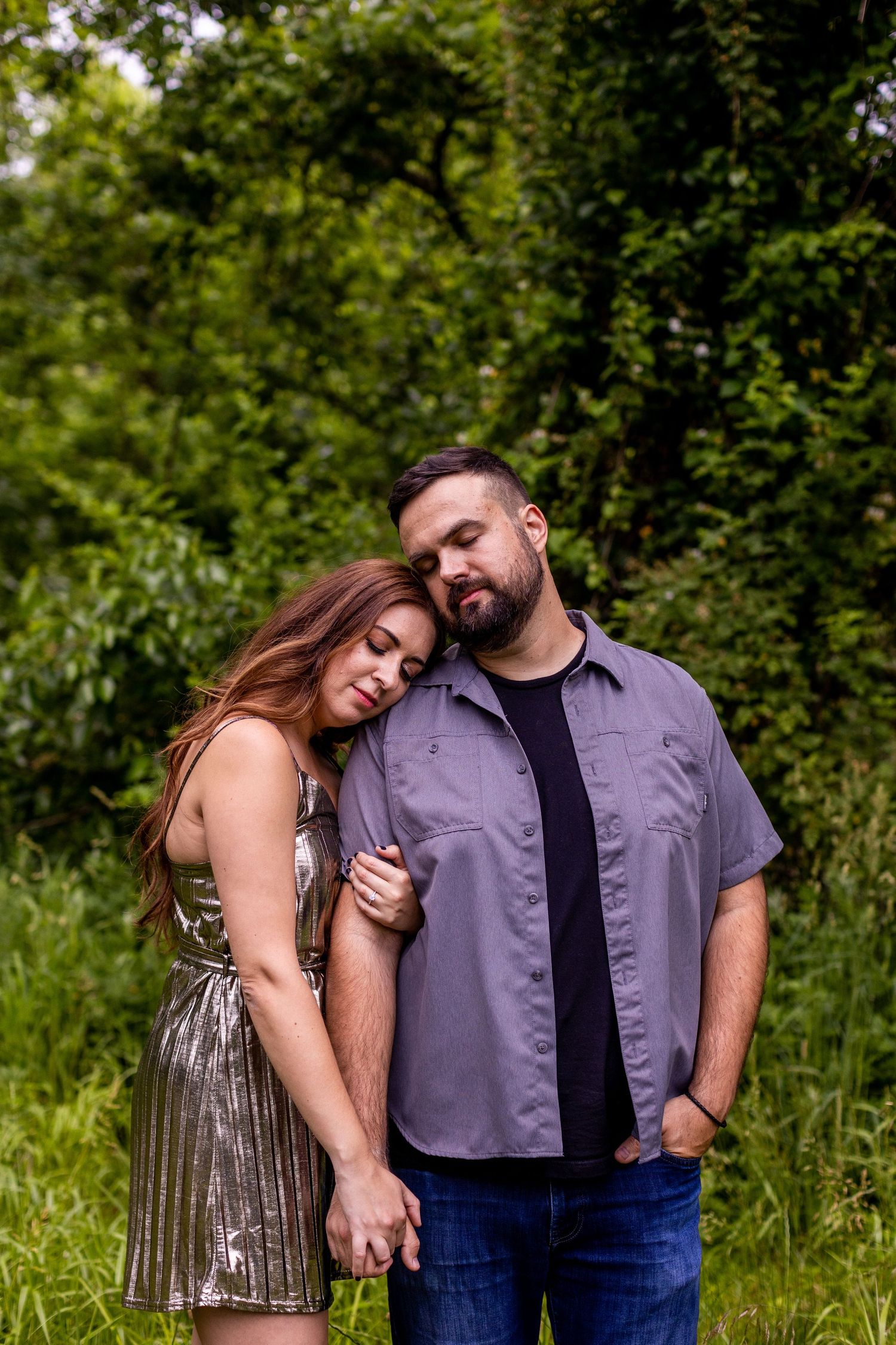 Couple shares tender moment in lush green outdoor setting.