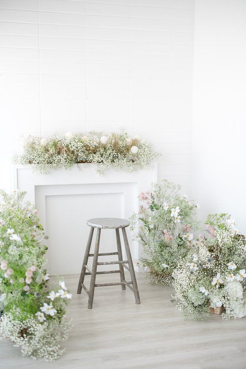 Rustic wooden stool against white backdrop with delicate floral arrangements and baby's breath.