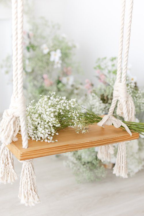 Wooden swing decorated with macrame ropes and baby's breath flowers.
