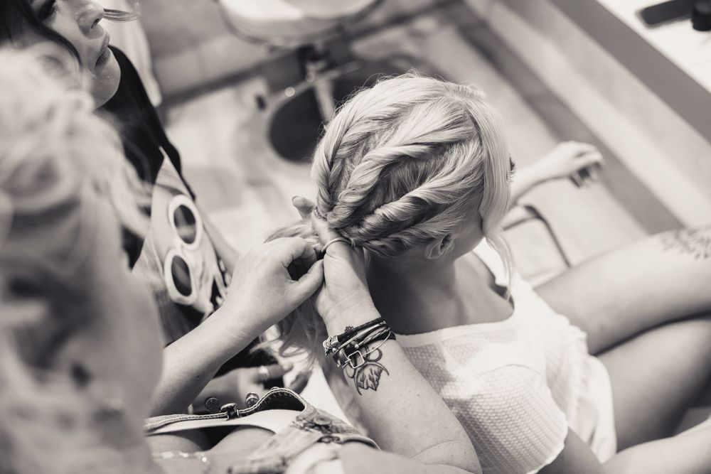 Intricate French braid hairstyle being styled in black and white photography.