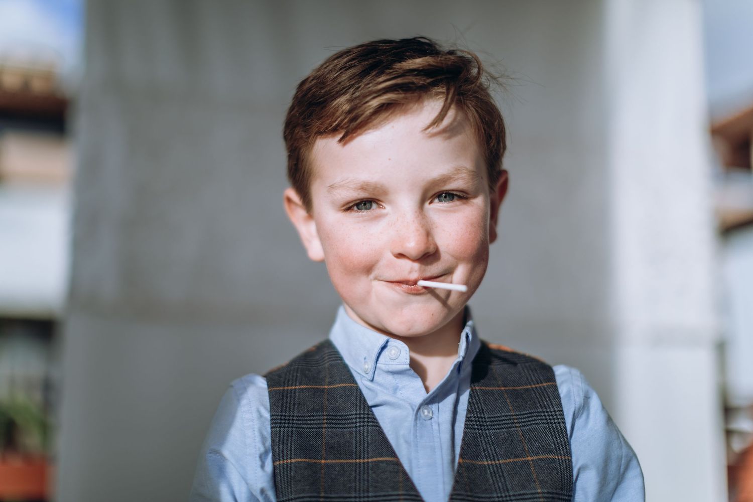 Boy smiling at the camera with a lollipop in his mouth.