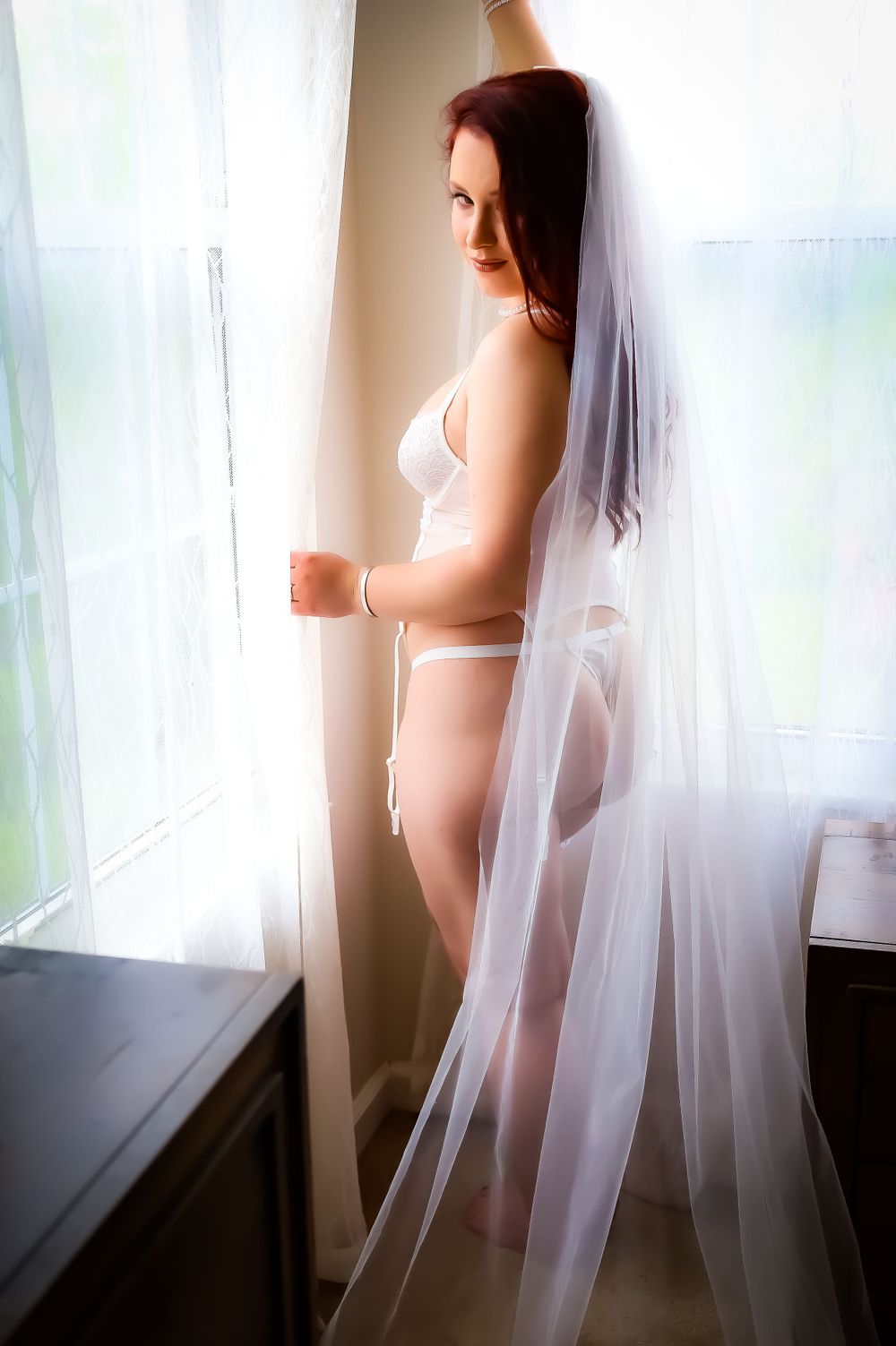 Ethereal silhouette against window with flowing white veil.
