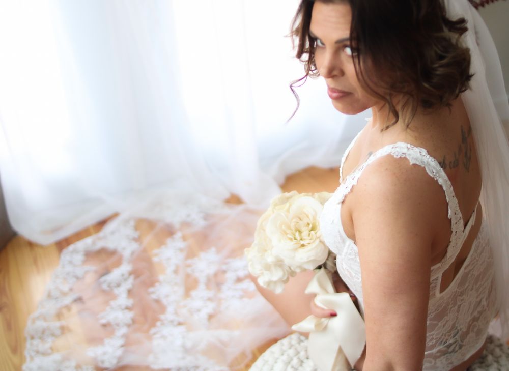 Romantic bridal portrait with cream roses and lace dress details in natural window light.