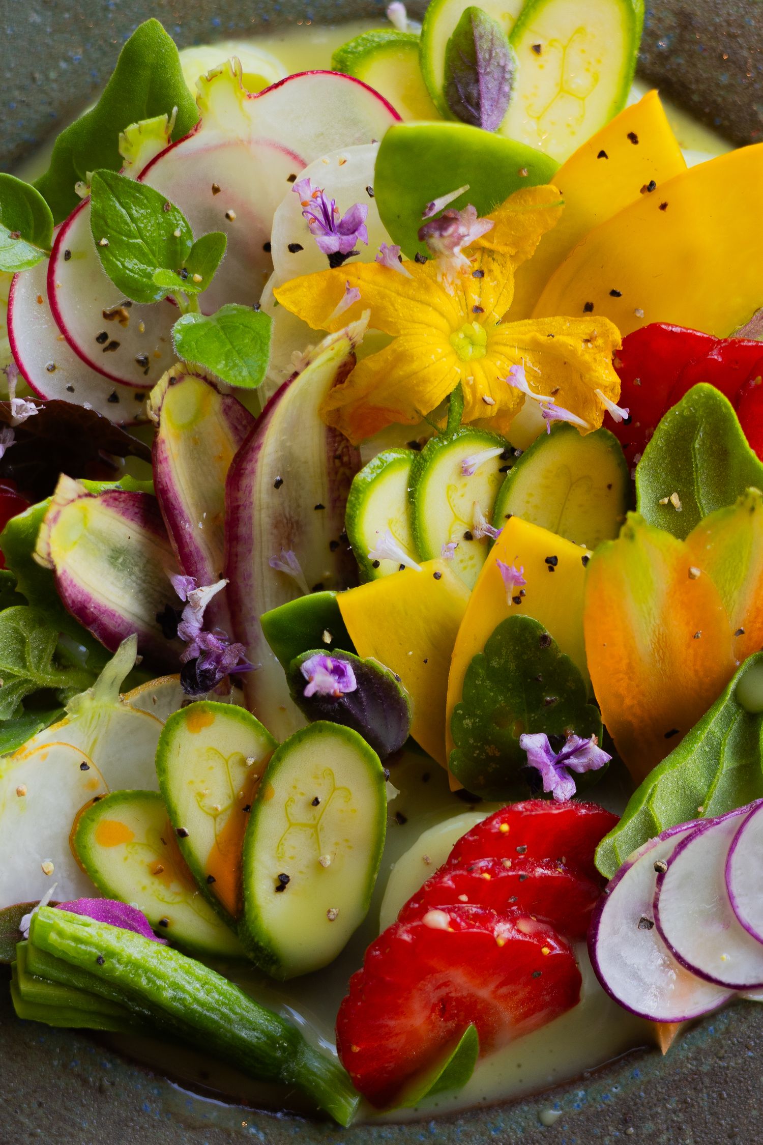 Colorful garden salad with radishes, cucumber slices, and edible flowers arranged artistically.
