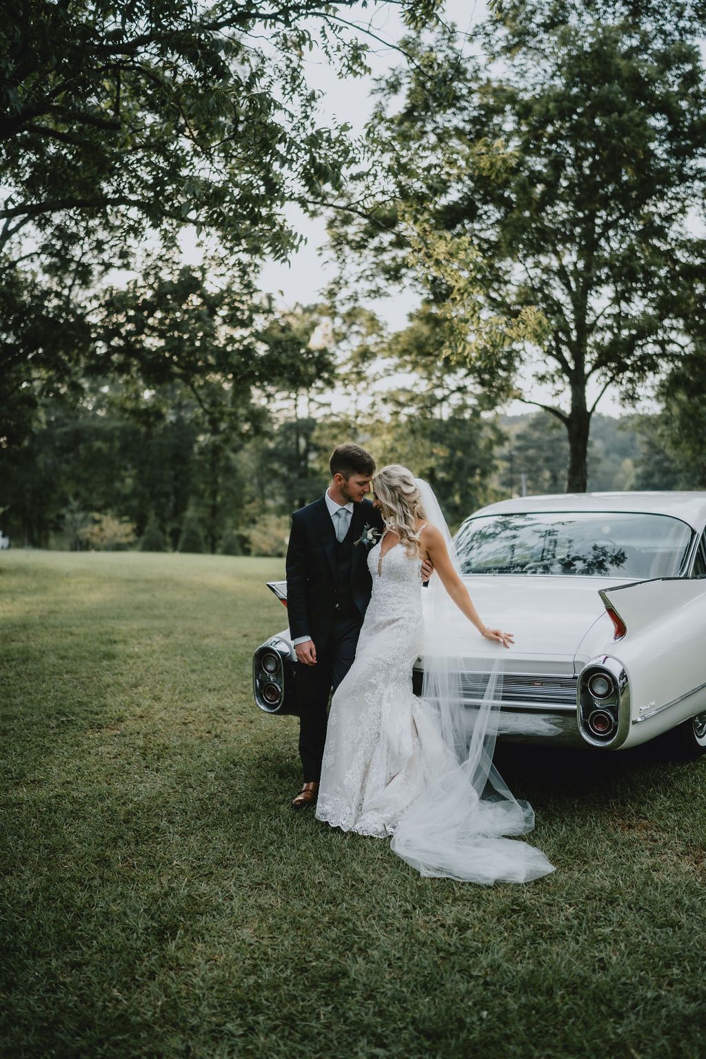 bride and groom up against old car