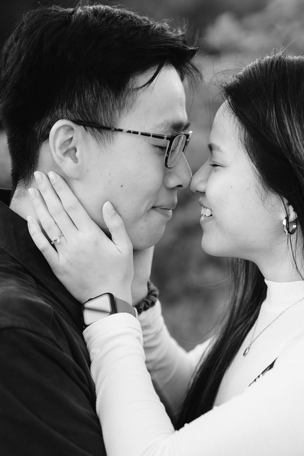 An intimate black and white portrait of a couple in a tender embrace.