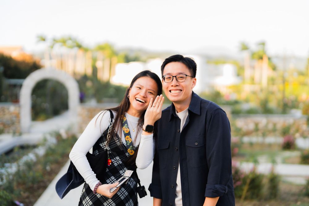 A joyful couple laughs together in a garden setting during golden hour.
