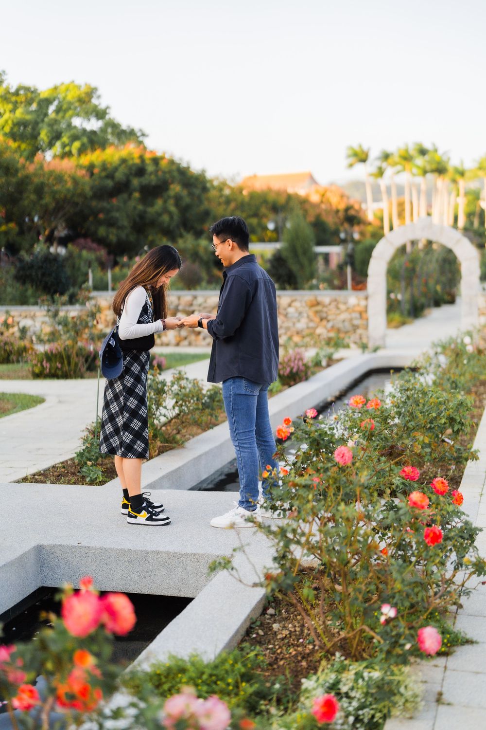 A couple shares a special moment on garden steps surrounded by blooming roses.