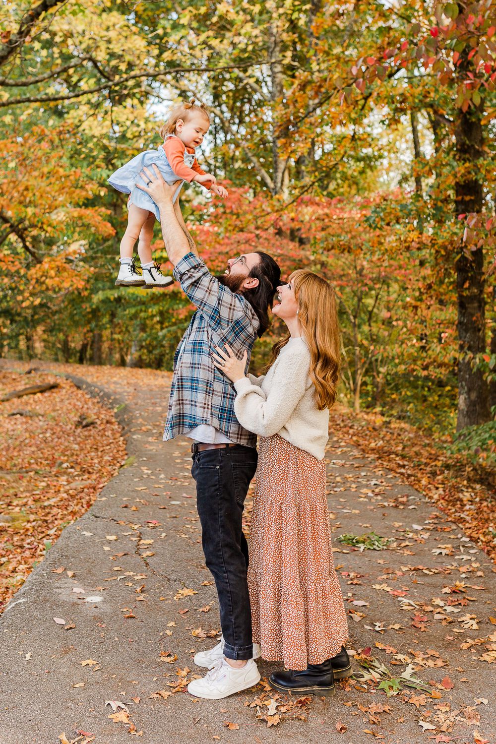 Fun family moment on a leaf-covered path during autumn.