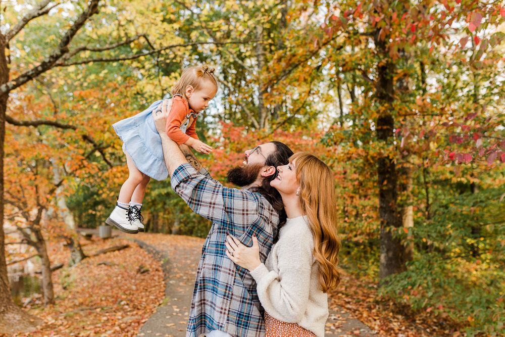 Playful interaction on a pathway surrounded by autumn leaves and trees.