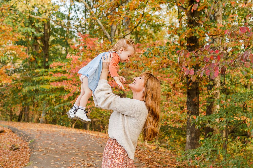 Playful moment captured between parent and child against vibrant fall foliage.