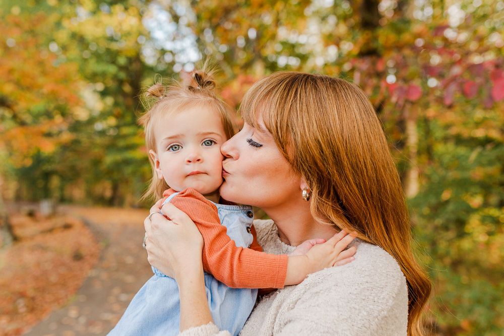 Intimate moment between parent and child against fall foliage background.