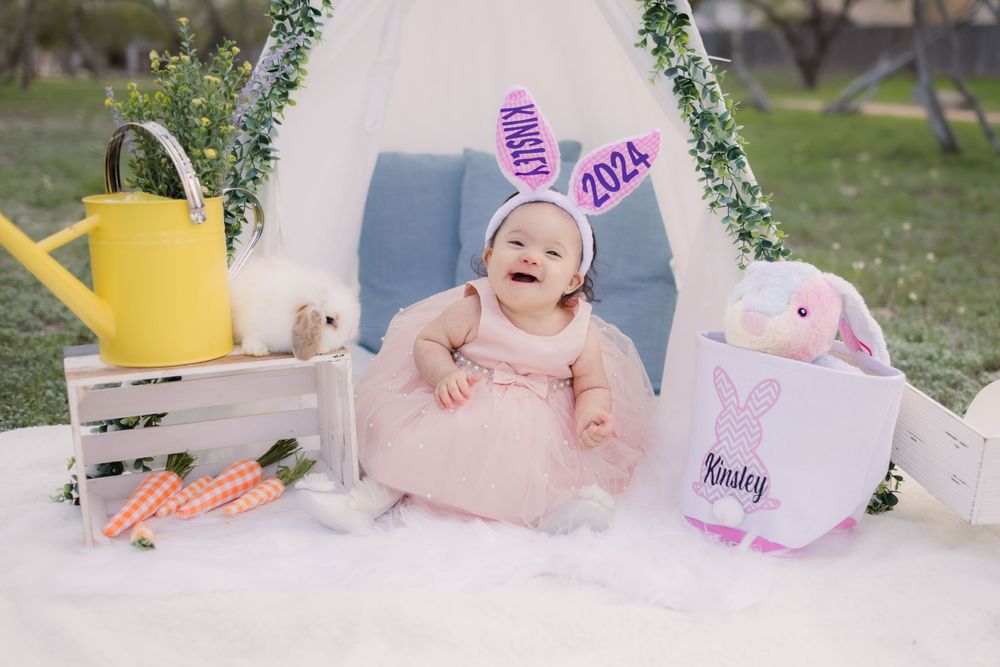 White teepee tent decorated with greenery and yellow watering can creates spring photo setting.