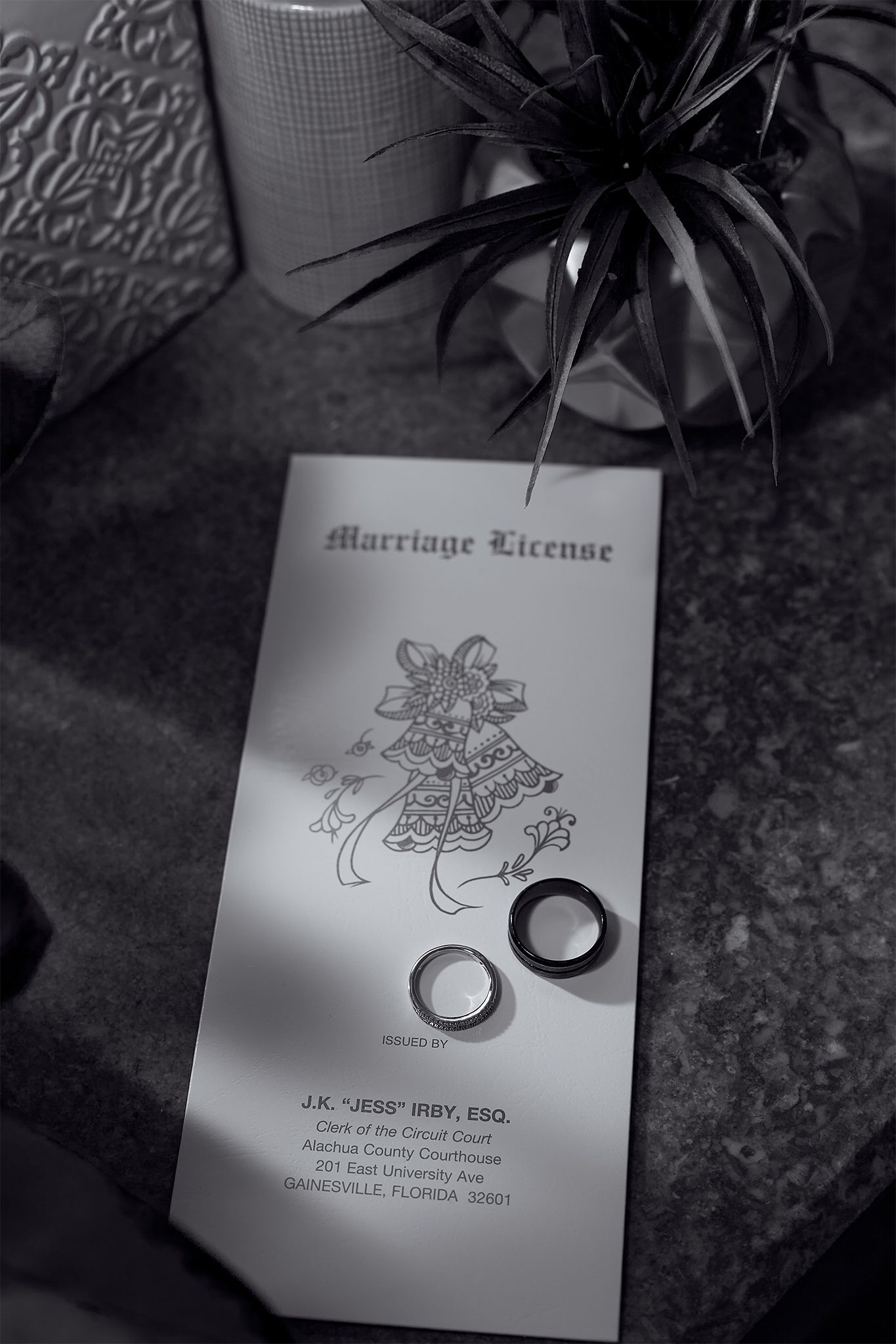 A marriage license with wedding rings and decorative floral design captured in black and white.