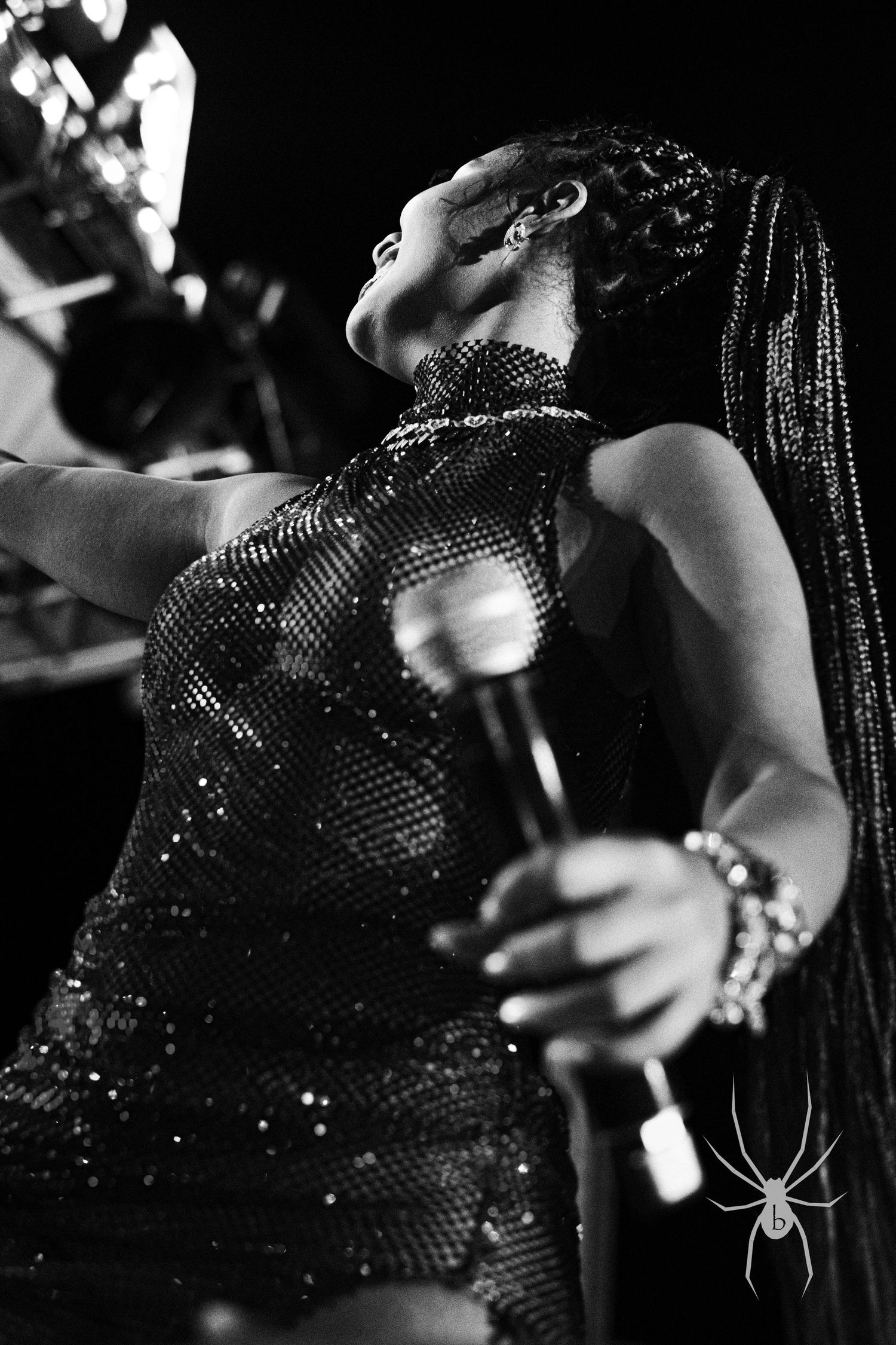 Performer in a sequined dress singing passionately during a dramatic stage performance.