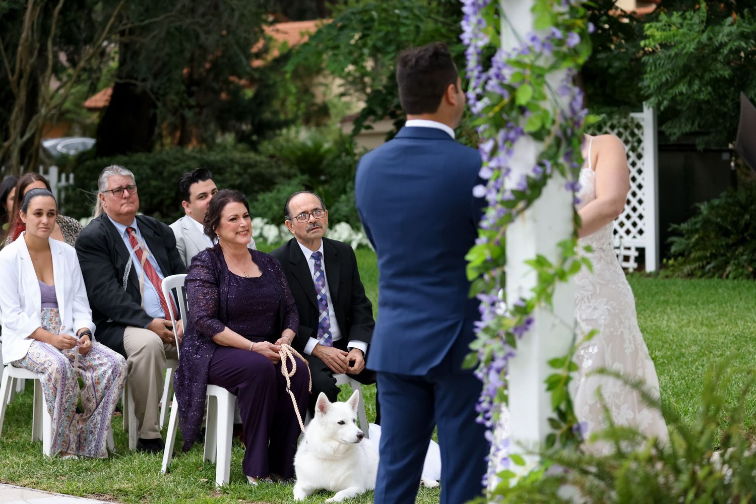 Outdoor wedding ceremony setup with guests seated facing a floral-decorated arch.