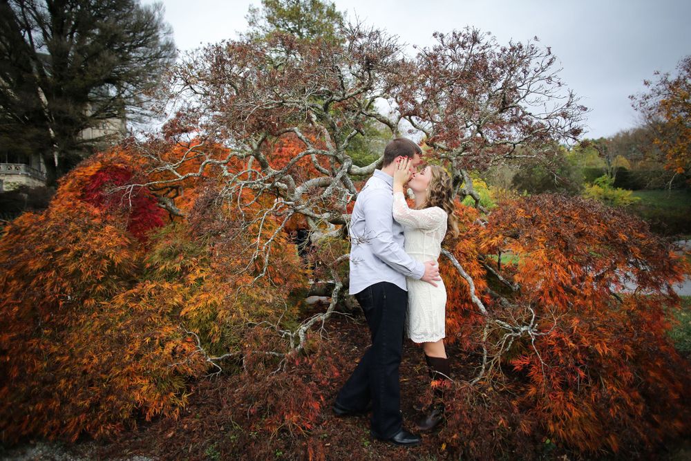 Autumn engagement photoshoot with vibrant red and orange foliage.