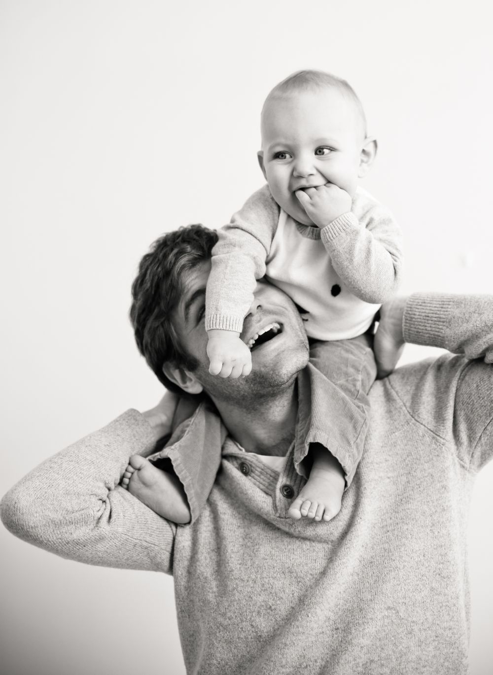 A joyful black and white portrait of a parent and baby playing together.