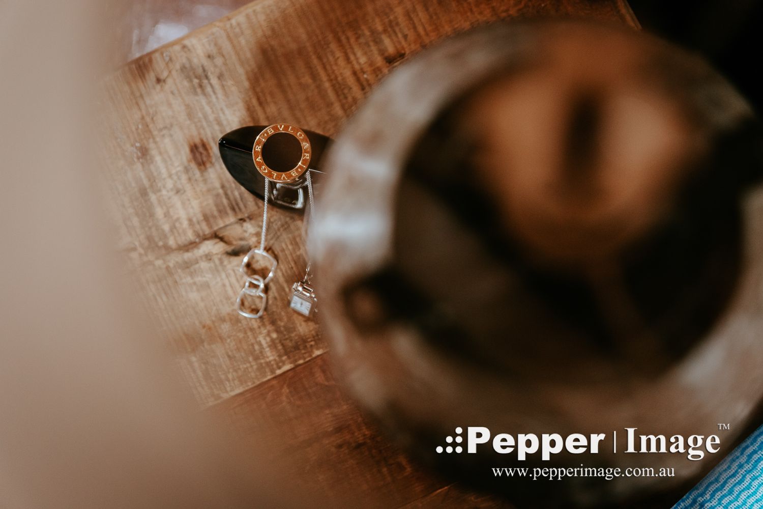 Close-up of elegant wedding jewelry including rings and earrings on a rustic wooden surface.