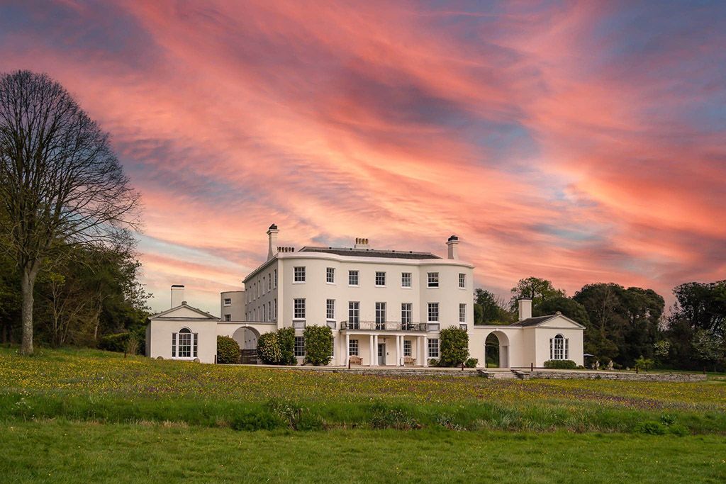 Sunset sky over Rockbeare Manor cream looking mansion. Rockbeare Manor Wedding photographer