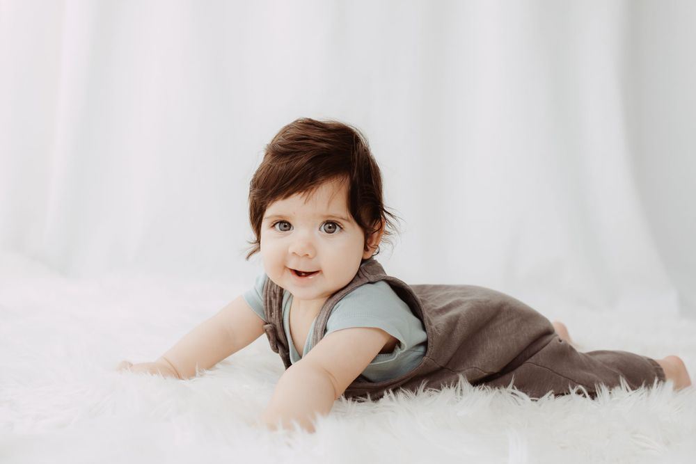 Candid lifestyle photography of a young child playing on white bedding.