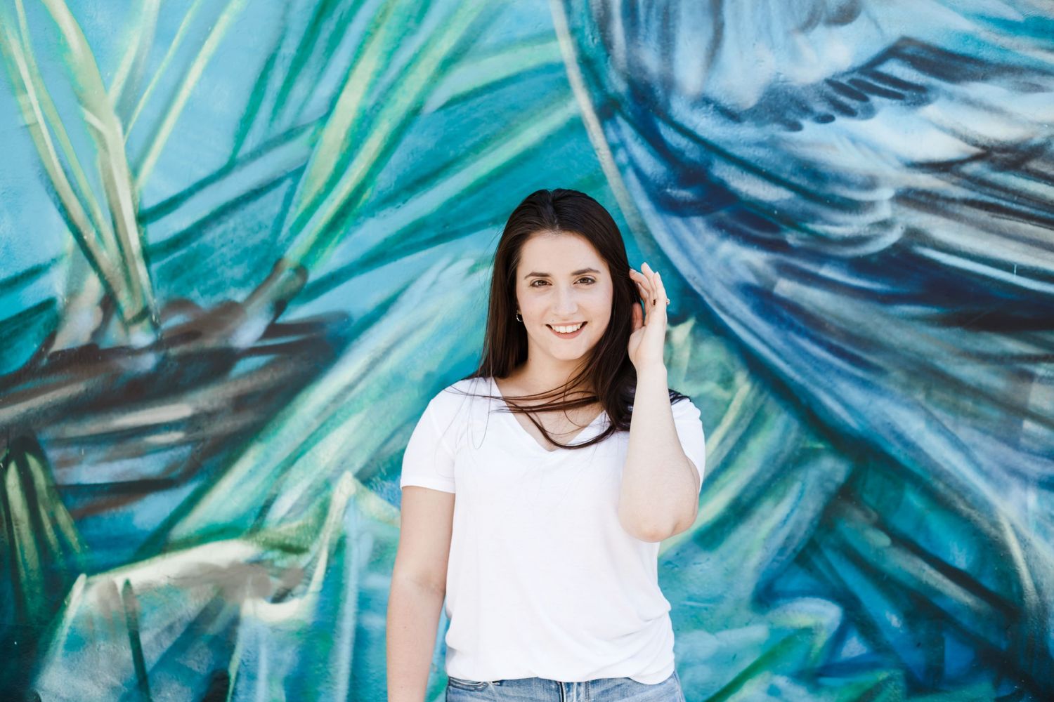 Woman posing in casual attire against vibrant blue and green mural wall background in downtown Harrisburg, PA.