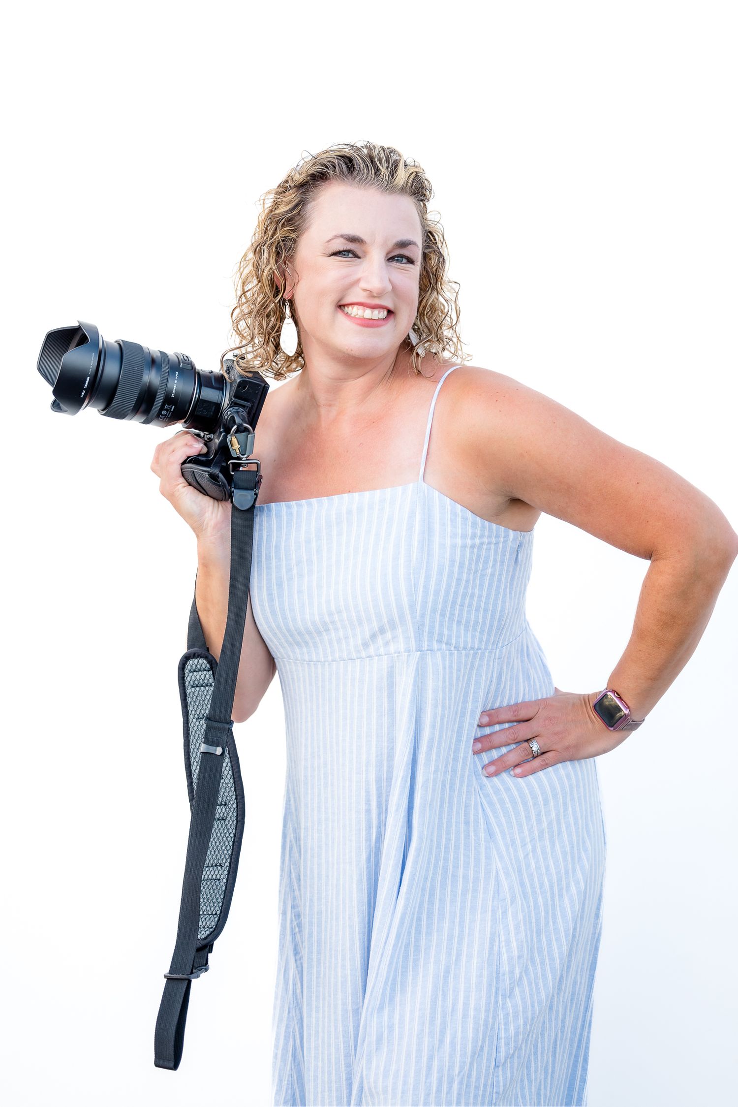 Stephanie Coulter in striped summer dress smiles while holding professional camera equipment by Christina Gabaldon Photography