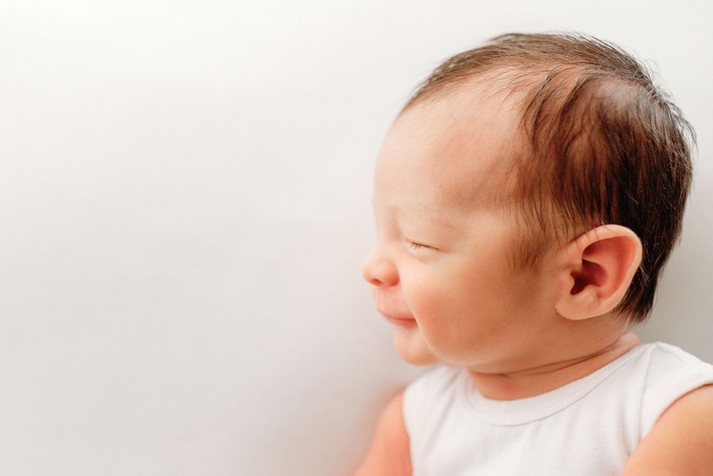 Side profile of sleeping newborn against white background.