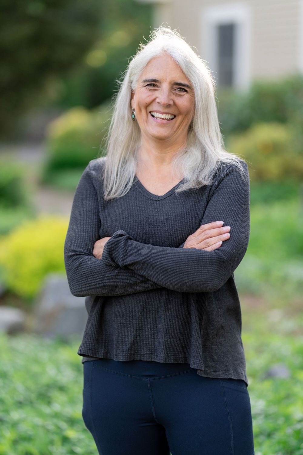 Cheerful outdoor portrait wearing dark sweater against garden background.