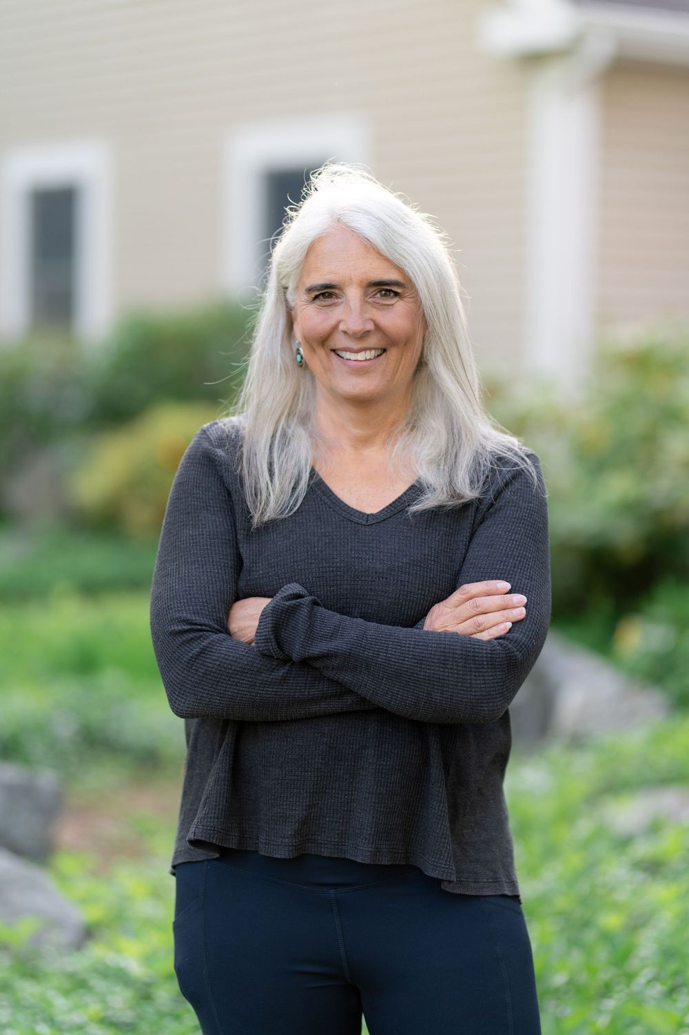 Casual portrait in dark v-neck sweater against landscaped garden setting.