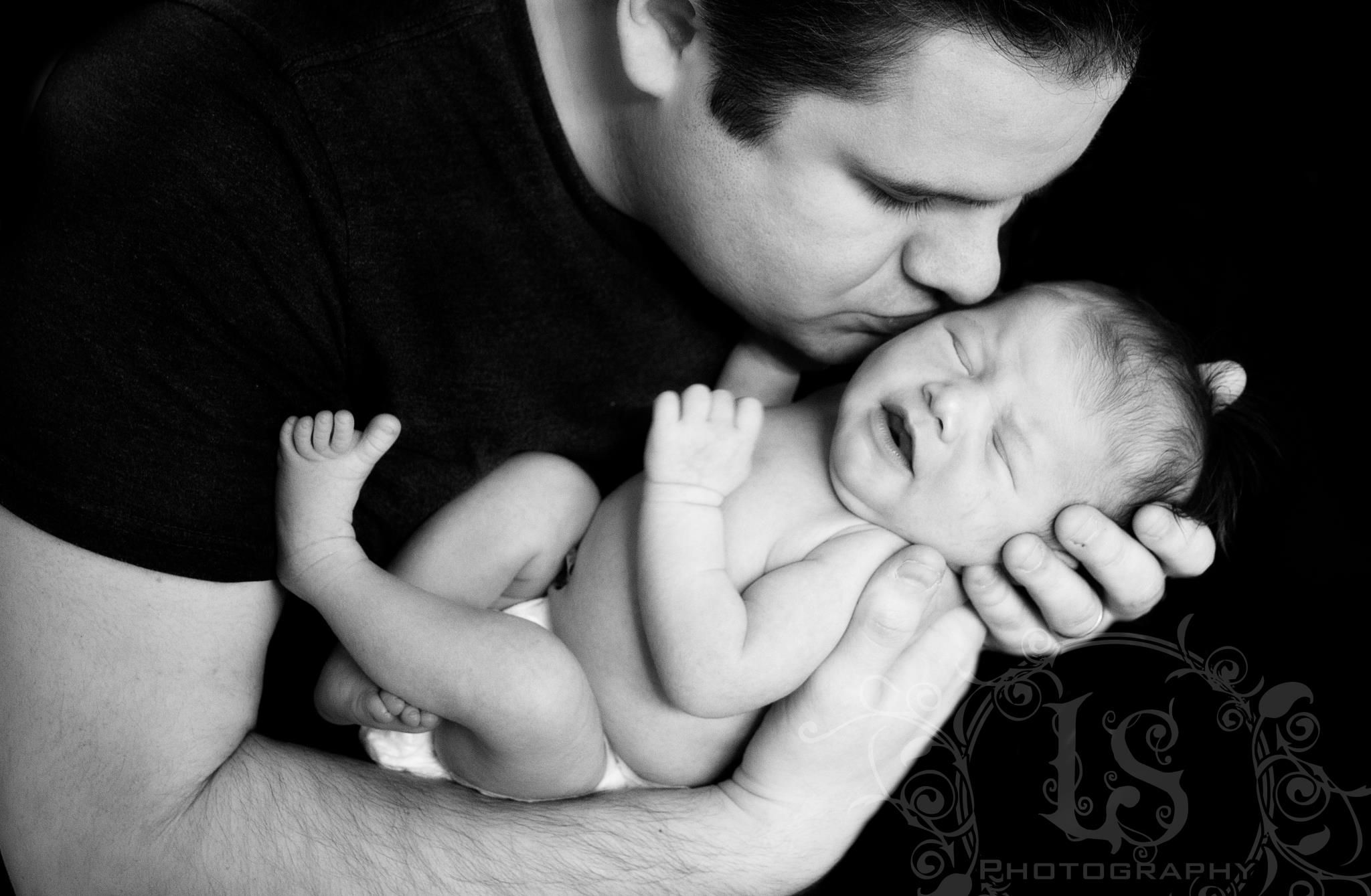 A tender black and white portrait of a parent cradling a newborn baby.