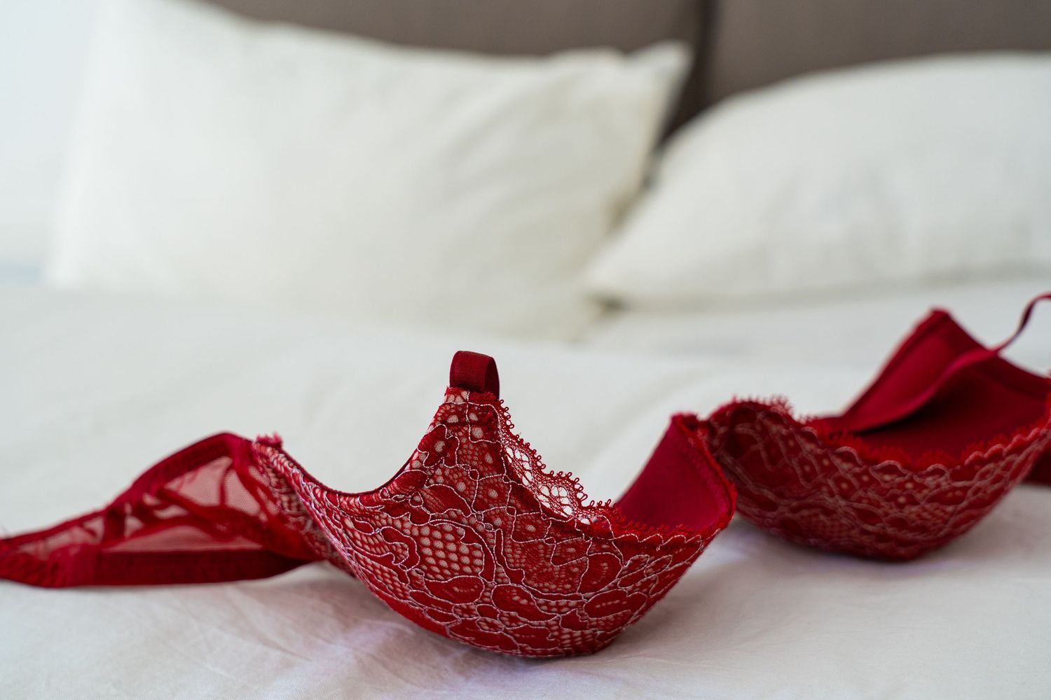 Boudoir By Elise- what to wear to boudoir photo shoot, Red lace bra lying on white bed sheets.