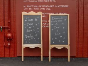 Rustic red barn wall with multiple chalkboard signs mounted in a row showing wedding details.