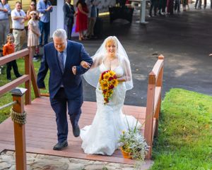 A couple walks down a brick pathway surrounded by greenery during their wedding.