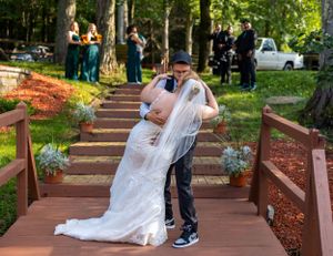 Wedding couple posing on wooden steps surrounded by green landscaping.