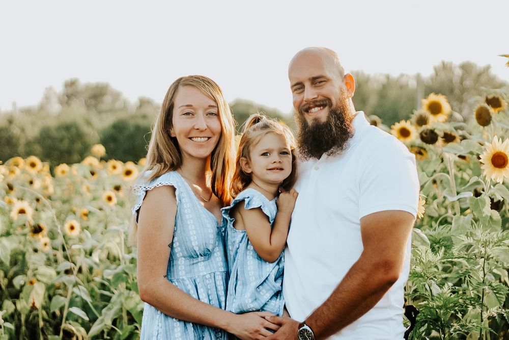 Family enjoying quality time together surrounded by blooming sunflowers in warm evening light.