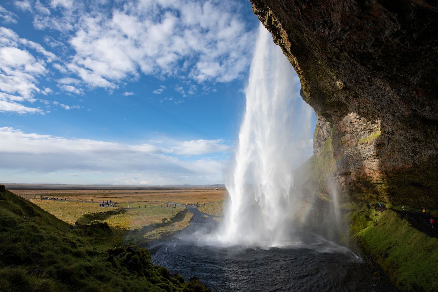 Seljalandsfoss waterfall in Iceland, where you can walk behind the 200-foot, volcanic glacier-fed waterfall cascading from a sheer cliff.