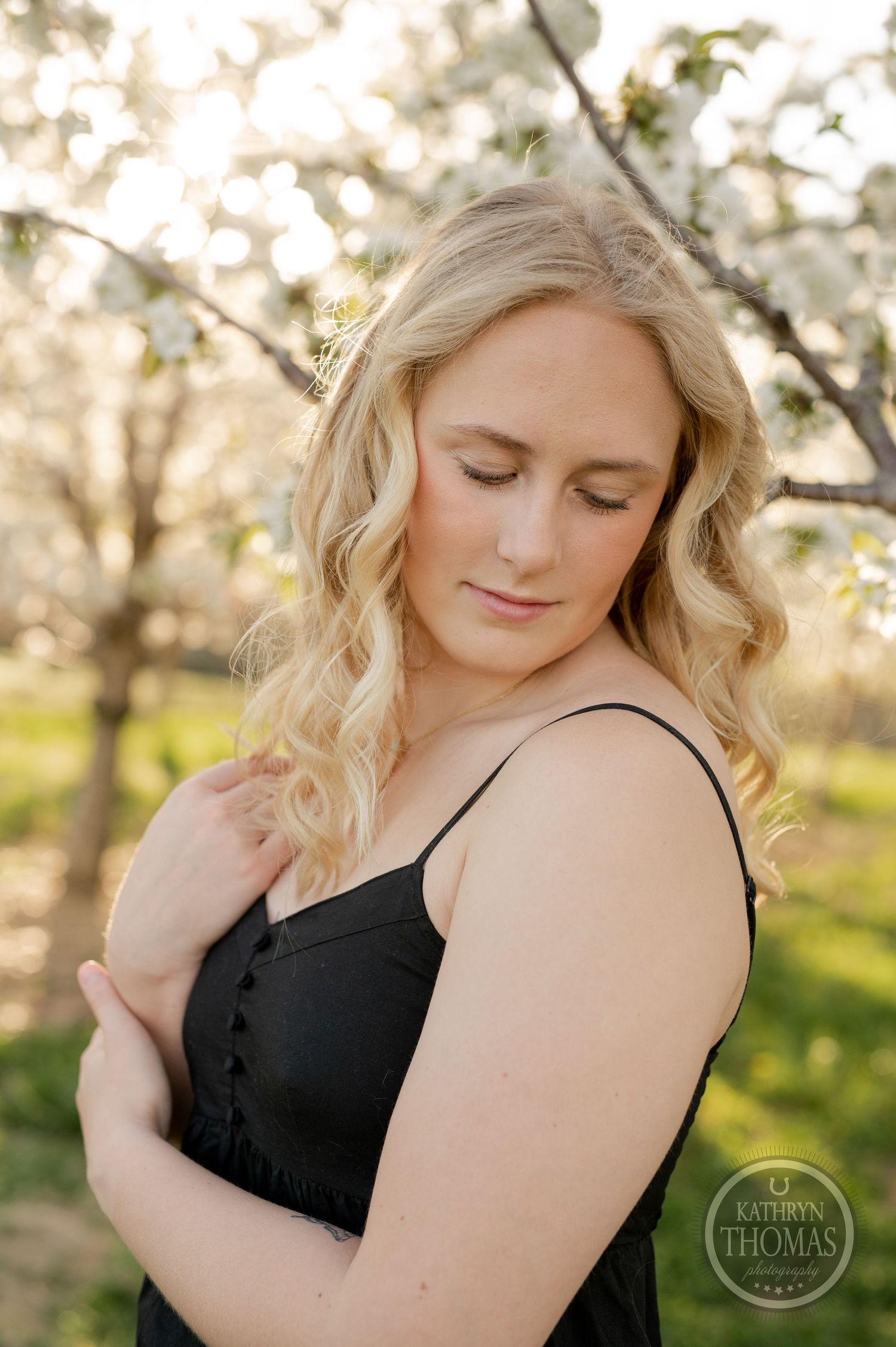 Soft portrait in a blooming spring orchard with delicate white blossoms in the background.