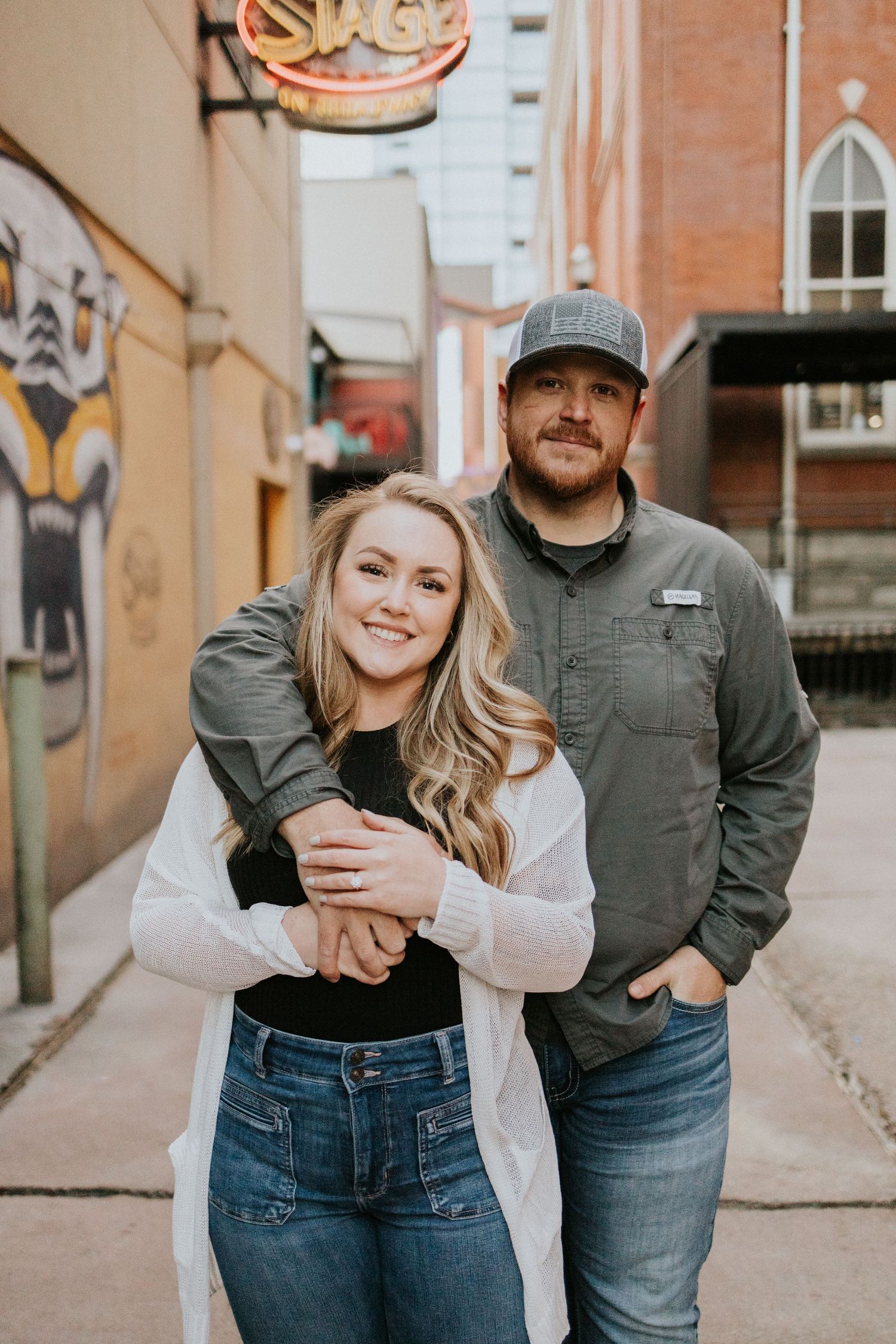 A casual couple poses in an urban alley with street art and brick walls.