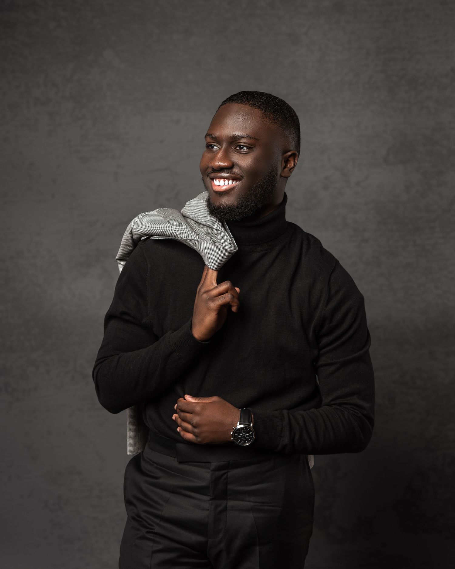 Studio portrait of someone in black turtleneck and grey scarf against dark background.